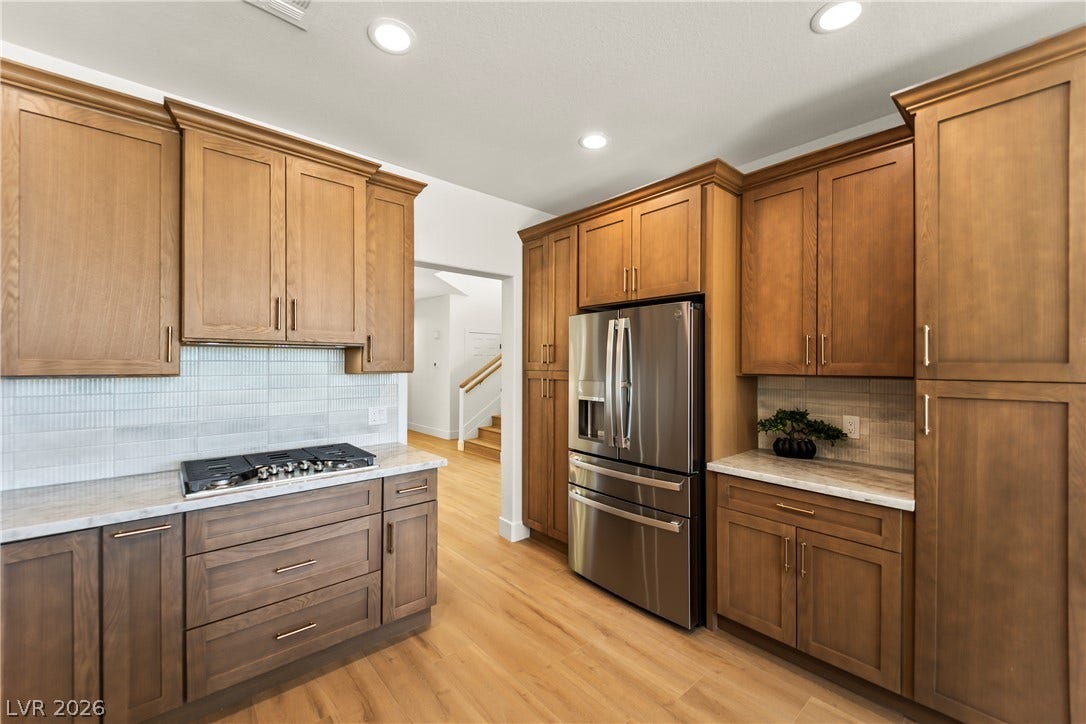 8921 Diamond Falls Drive, Las Vegas, NV 89117 A pristine kitchen offers warm wooden cabinetry and modern stainless steel appliances for elegant meal preparation.