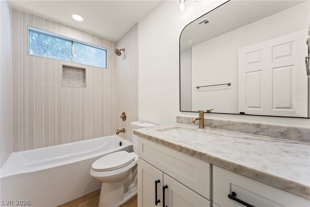 8921 Diamond Falls Drive, Las Vegas, NV 89117 A well-appointed bathroom features a single vanity with stone counters and a tub/shower combination with tiled walls.