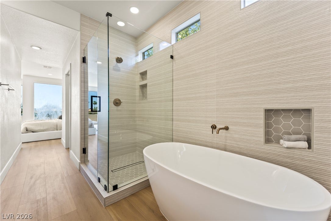 8921 Diamond Falls Drive, Las Vegas, NV 89117 Indulge in a serene primary bathroom featuring a freestanding tub and a glass-enclosed shower.