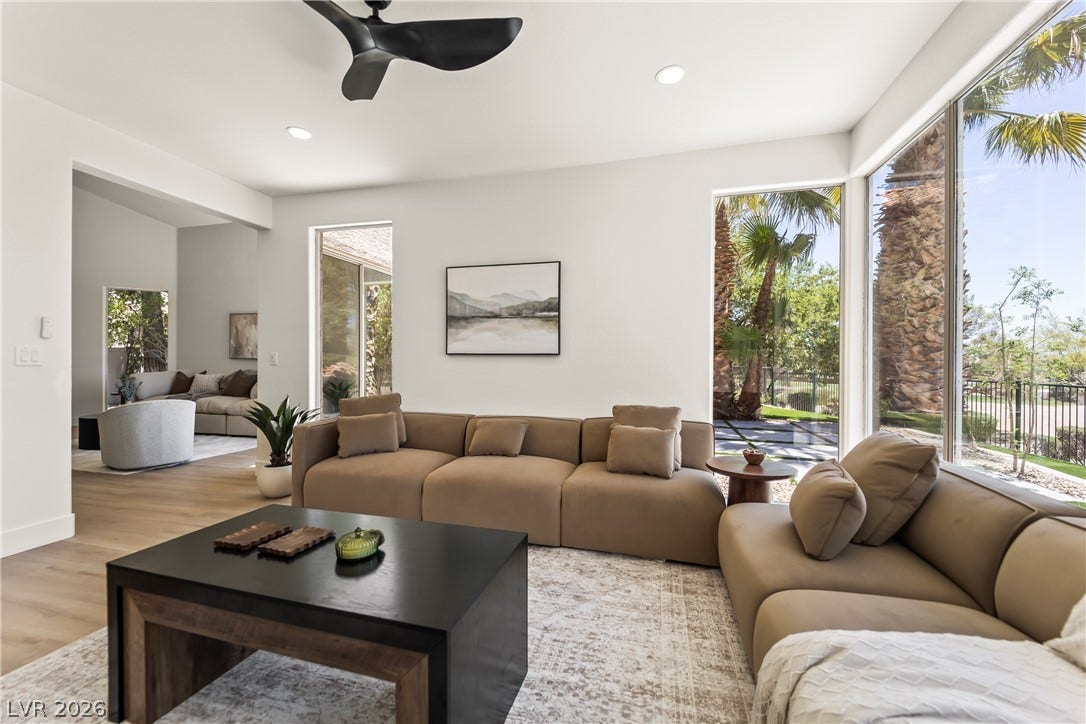 8921 Diamond Falls Drive, Las Vegas, NV 89117 Floor-to-ceiling windows flood this modern living room with natural light and offer inspiring views of the lush outdoors.