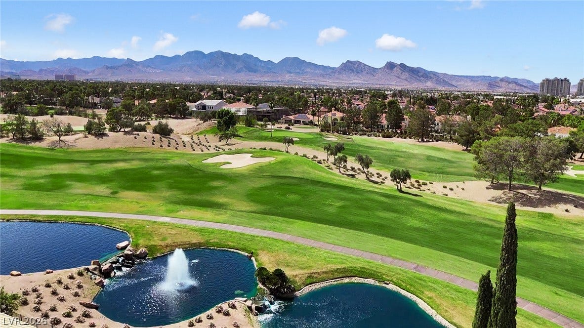 8921 Diamond Falls Drive, Las Vegas, NV 89117 A picturesque golf course and water features are set against a backdrop of distant mountains and clear skies.