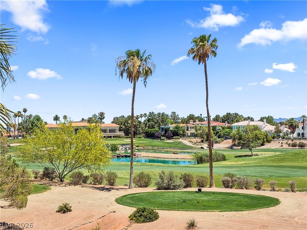 8921 Diamond Falls Drive, Las Vegas, NV 89117 A vibrant golf course view features verdant fairways, shimmering water, and distant luxury residences under a clear sky.