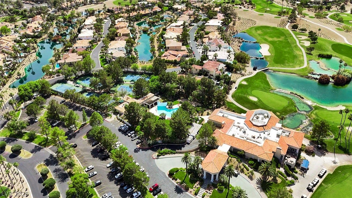 8921 Diamond Falls Drive, Las Vegas, NV 89117 An aerial panorama reveals a vibrant golf course community, complete with homes, tennis courts, and glistening waterways.