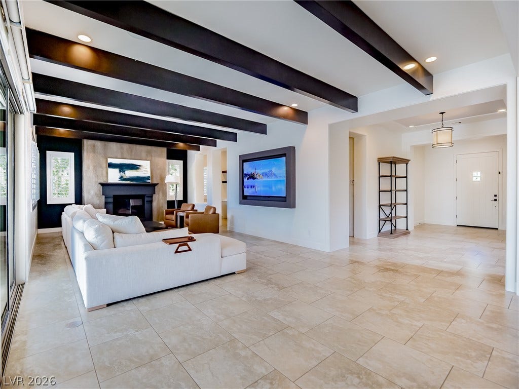 12013 Tramonto Avenue, Las Vegas, NV 89138 Bold ceiling beams draw the eye across this tile-floored living area toward a fireplace.