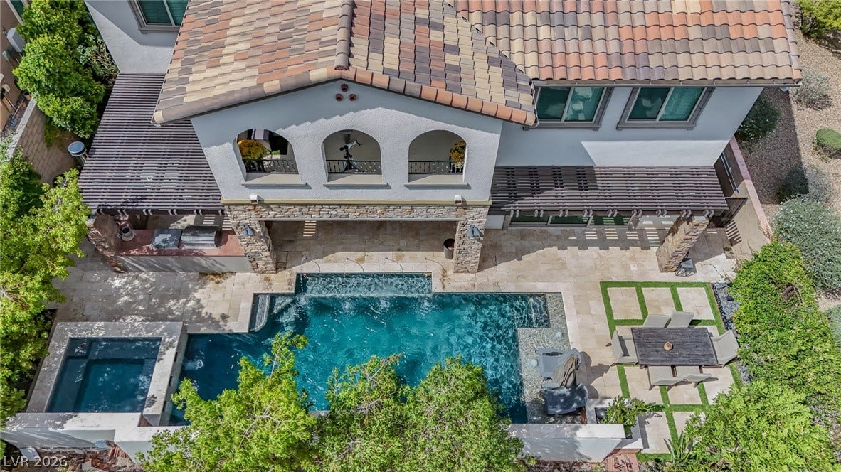 12013 Tramonto Avenue, Las Vegas, NV 89138 An inviting backyard oasis showcases a sparkling pool alongside stone accents and a tiled roofline.