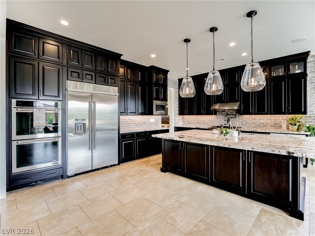 12013 Tramonto Avenue, Las Vegas, NV 89138 Rich dark cabinetry contrasts beautifully with granite countertops and a tiled floor.