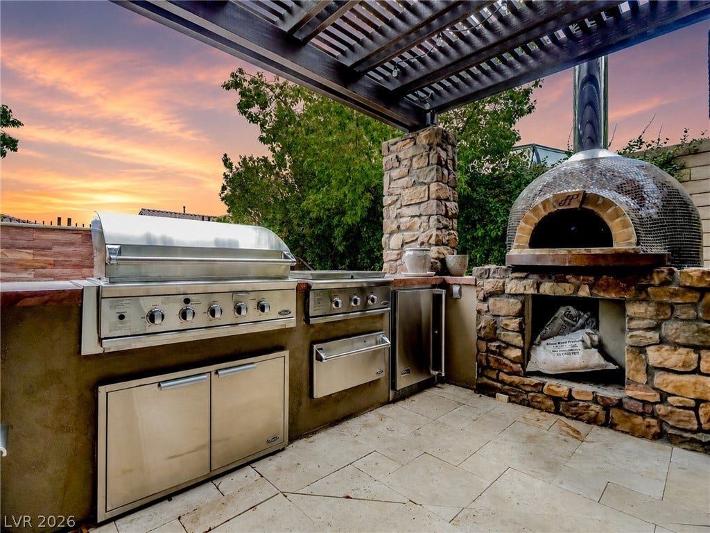12013 Tramonto Avenue, Las Vegas, NV 89138 Stone accents and a custom pergola define this exceptional outdoor kitchen area.
