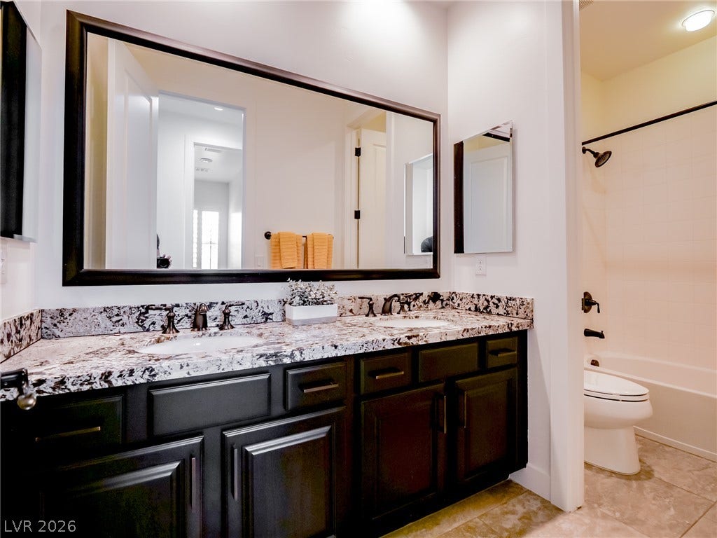 12013 Tramonto Avenue, Las Vegas, NV 89138 Double vanities with stone counters flank a classic tub and shower combination.