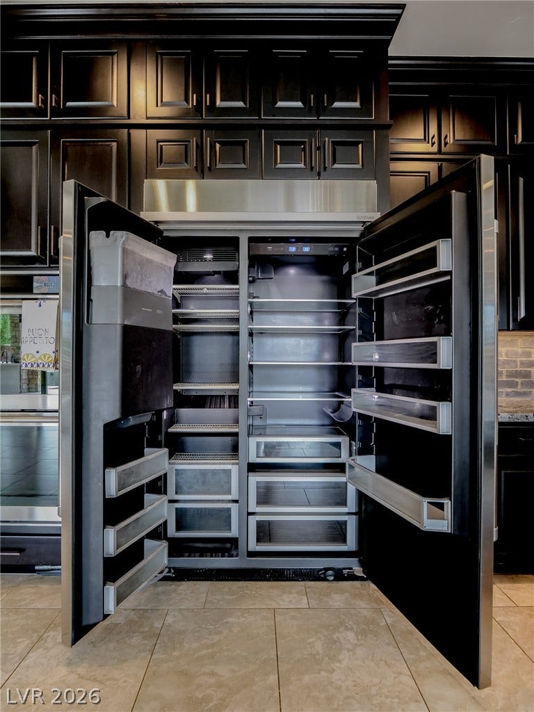 12013 Tramonto Avenue, Las Vegas, NV 89138 Dark cabinetry framing a modern, integrated refrigerator creates a sleek culinary focal point.
