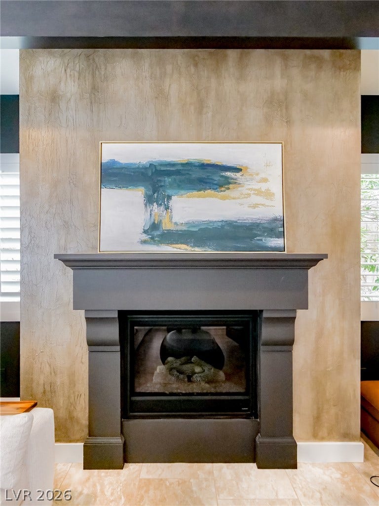 12013 Tramonto Avenue, Las Vegas, NV 89138 An elegant fireplace anchors the room, framed by textured plaster wall detailing and tile flooring.