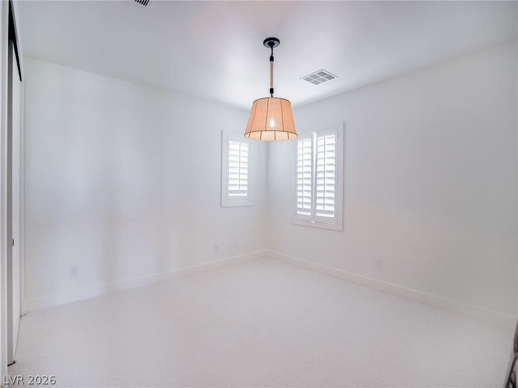 12013 Tramonto Avenue, Las Vegas, NV 89138 Crisp white walls and plush carpeting create a serene atmosphere in this versatile bedroom.