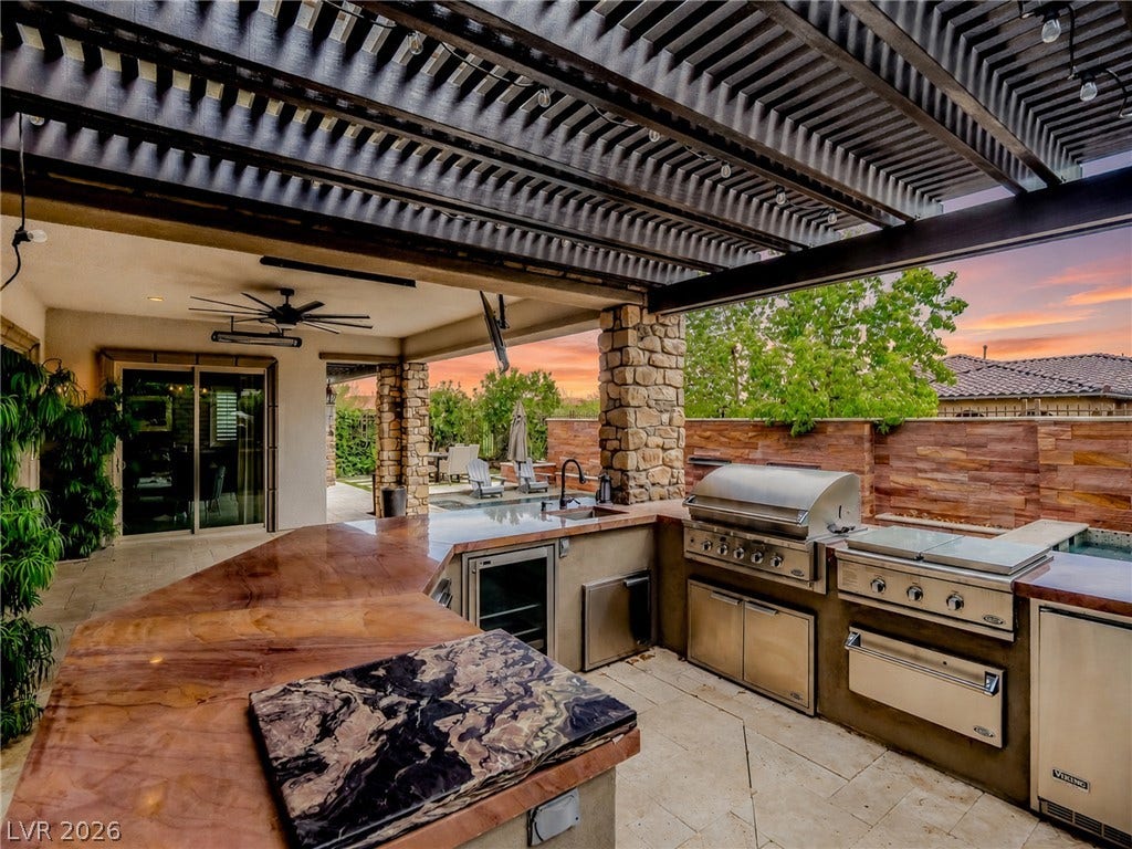 12013 Tramonto Avenue, Las Vegas, NV 89138 An outdoor kitchen features premium appliances and stone finishes beneath a modern louvered pergola.