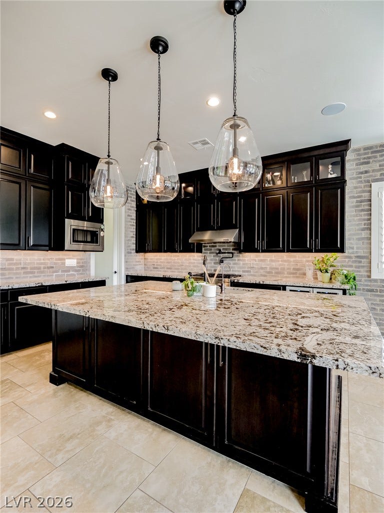 12013 Tramonto Avenue, Las Vegas, NV 89138 Gleaming granite countertops pair beautifully with dark cabinetry and textured tile flooring.