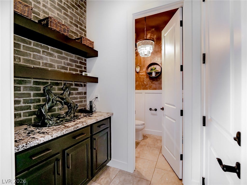 12013 Tramonto Avenue, Las Vegas, NV 89138 An elegant butler pantry features a stone countertop and textured brick wall accents.
