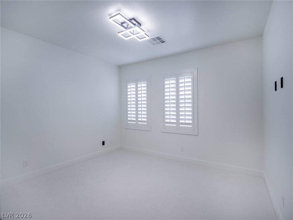 12013 Tramonto Avenue, Las Vegas, NV 89138 Crisp white walls and plush carpet define this versatile bedroom space.