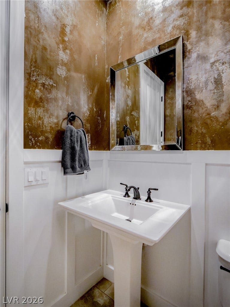 12013 Tramonto Avenue, Las Vegas, NV 89138 A classic pedestal sink sits against elegant white wainscoting and textured plaster walls.