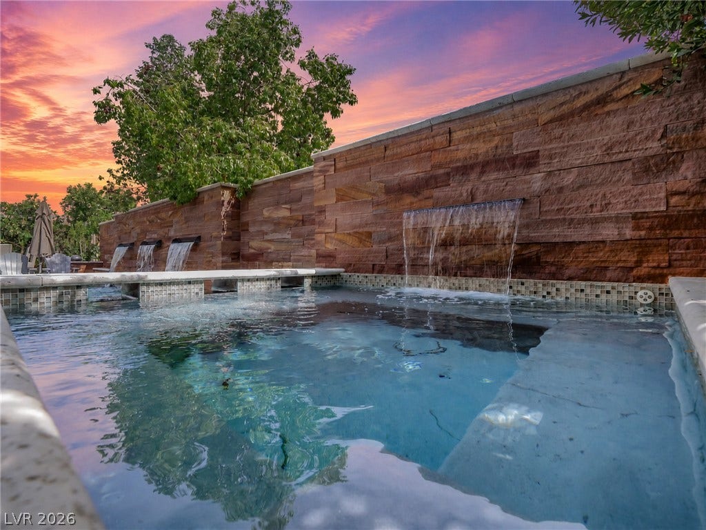 12013 Tramonto Avenue, Las Vegas, NV 89138 A tranquil stone wall with integrated water features borders this pristine custom swimming pool.