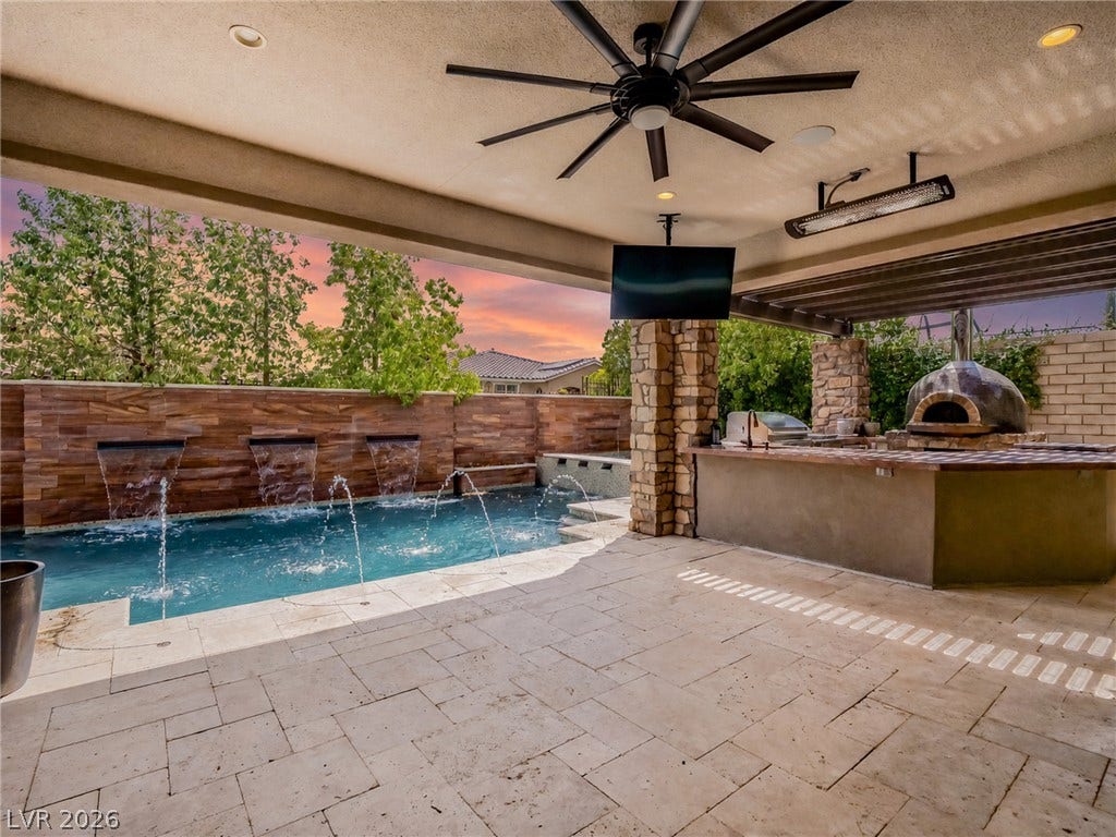 12013 Tramonto Avenue, Las Vegas, NV 89138 A spacious covered patio features tiled flooring alongside a built-in outdoor kitchen and sparkling pool.