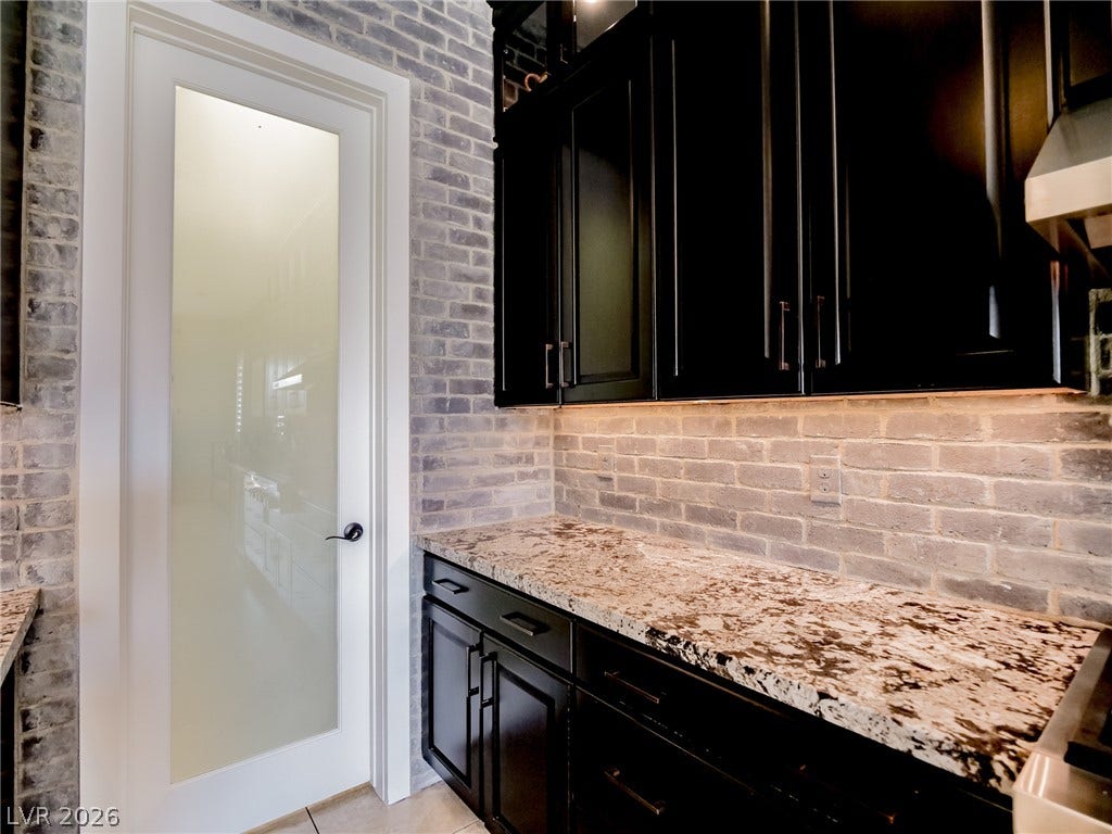 12013 Tramonto Avenue, Las Vegas, NV 89138 A frosted glass door opens to a walk-in pantry surrounded by textured brick walls.