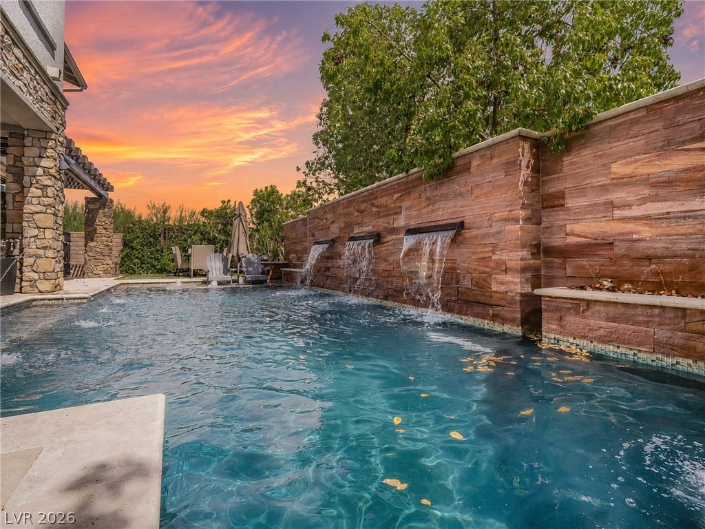 12013 Tramonto Avenue, Las Vegas, NV 89138 An inviting backyard pool features multi-tiered waterfalls flowing from a stone accent wall.