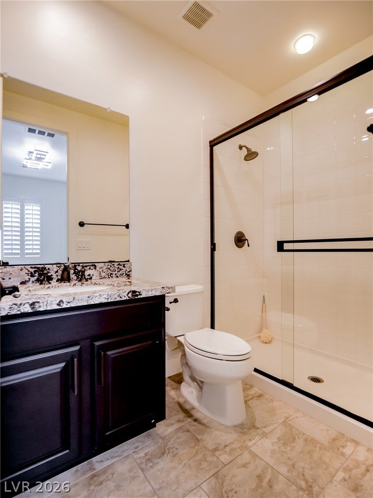 12013 Tramonto Avenue, Las Vegas, NV 89138 Granite counters and a tiled floor elevate this contemporary bathroom with a walk-in shower.