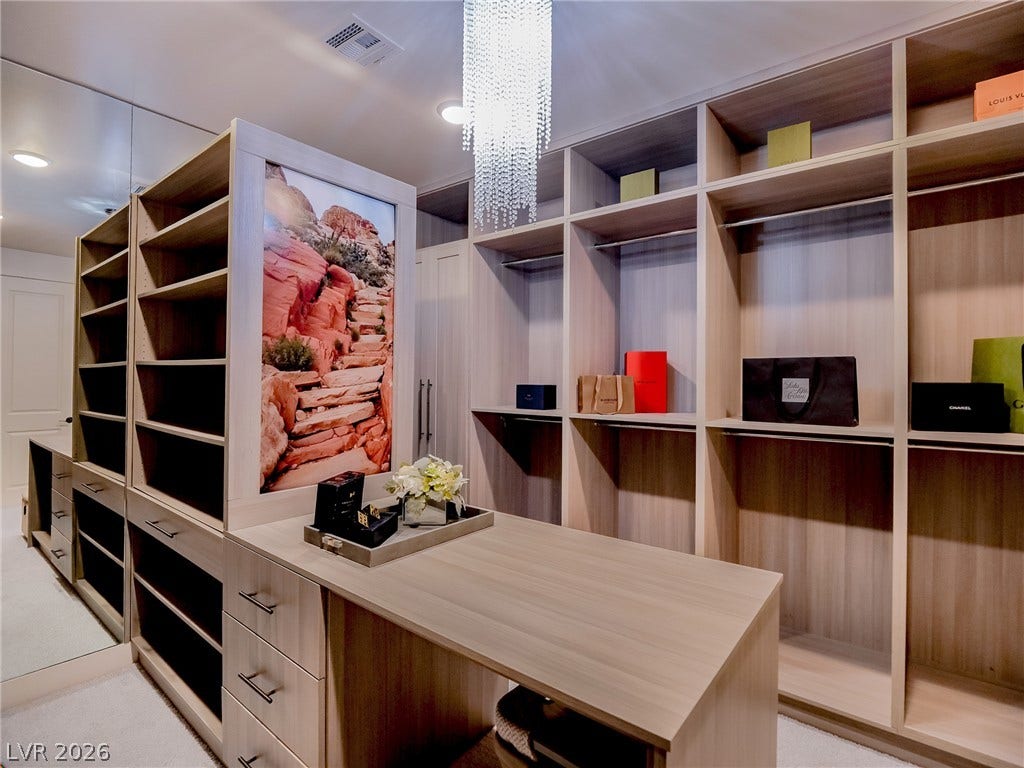 12013 Tramonto Avenue, Las Vegas, NV 89138 Custom built-in shelving and an integrated island maximize storage in this carpeted dressing room.