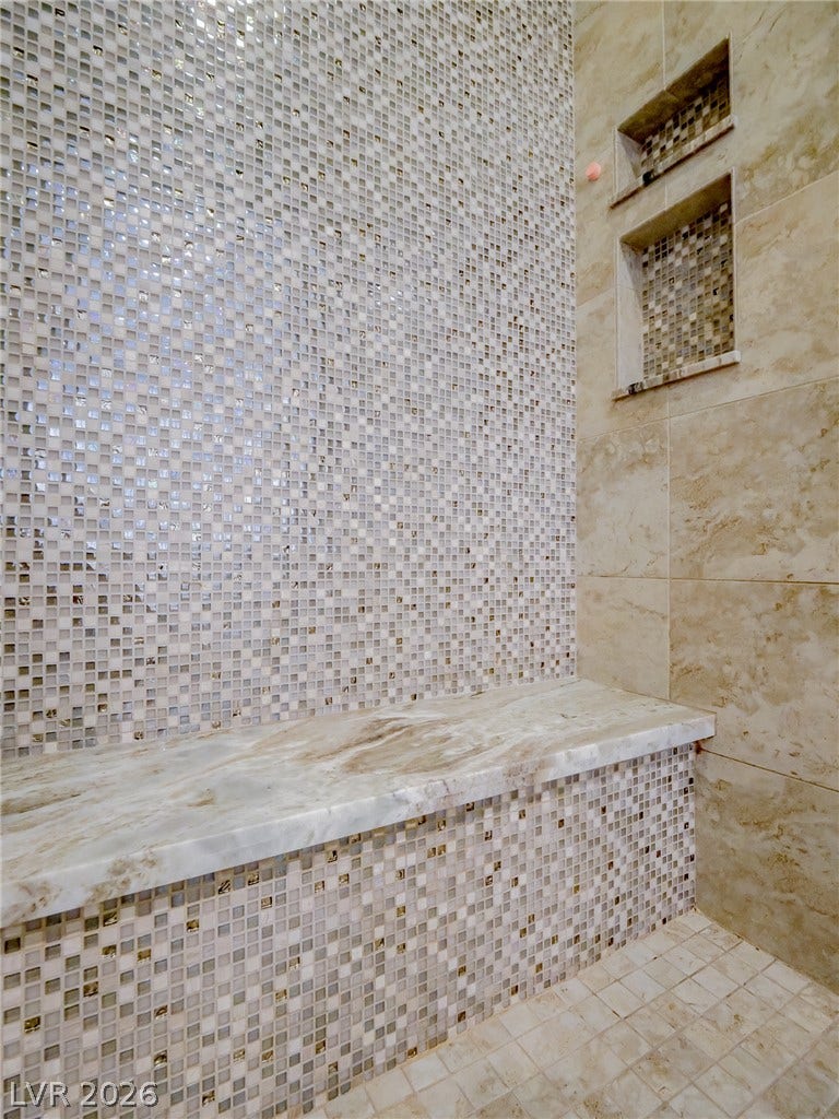 12013 Tramonto Avenue, Las Vegas, NV 89138 Meticulous tilework and a built-in stone bench define this walk-in shower design.
