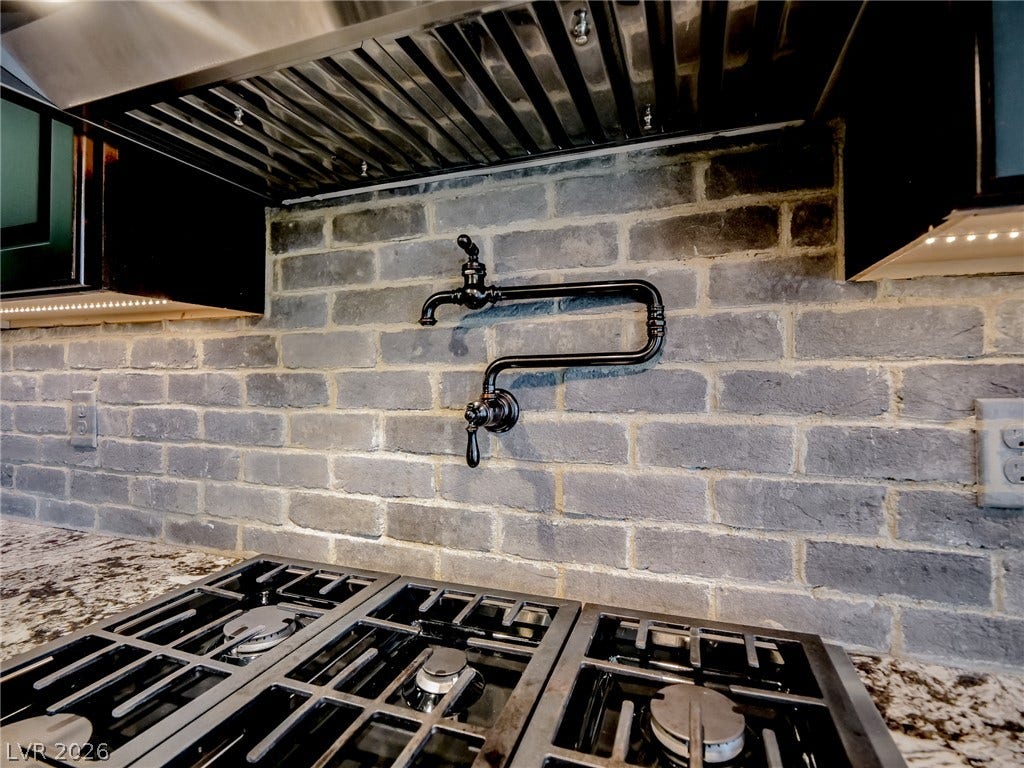 12013 Tramonto Avenue, Las Vegas, NV 89138 Exposed brick accents, stone countertops, and a convenient wall-mounted pot filler define this cooking area.