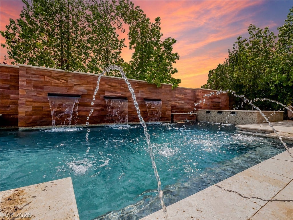 12013 Tramonto Avenue, Las Vegas, NV 89138 Cascading waterfalls and water jets accent this custom swimming pool framed by natural stone walls.