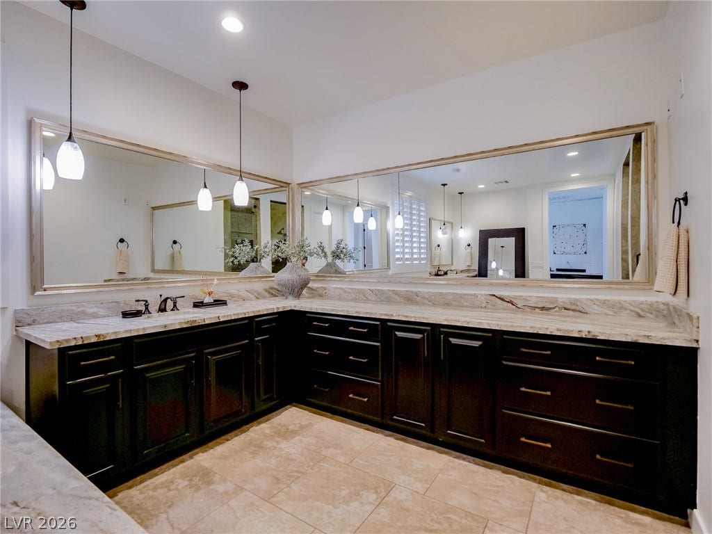 12013 Tramonto Avenue, Las Vegas, NV 89138 Gleaming stone countertops and dark cabinetry create a refined, expansive primary bath retreat.