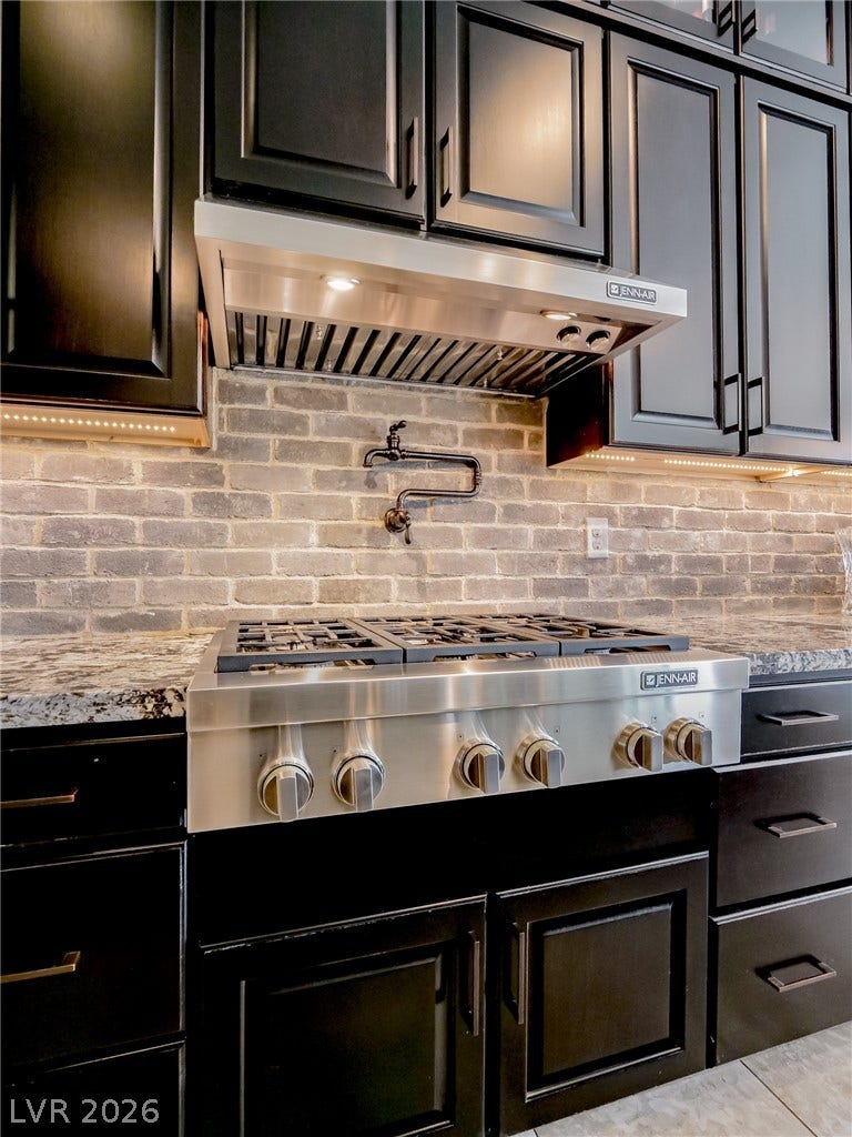 12013 Tramonto Avenue, Las Vegas, NV 89138 A modern gas range is complemented by custom cabinetry and a classic brick backsplash.