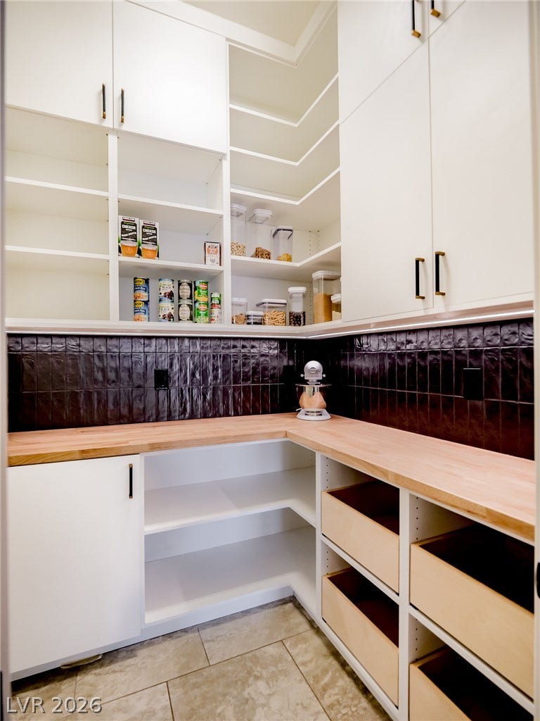 12013 Tramonto Avenue, Las Vegas, NV 89138 A well-organized walk-in pantry boasts wraparound wooden countertops and dark tile backsplashes.
