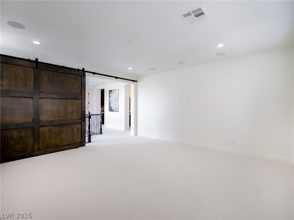 12013 Tramonto Avenue, Las Vegas, NV 89138 A spacious upper-level loft features fresh carpet and a character-rich wooden sliding barn door.