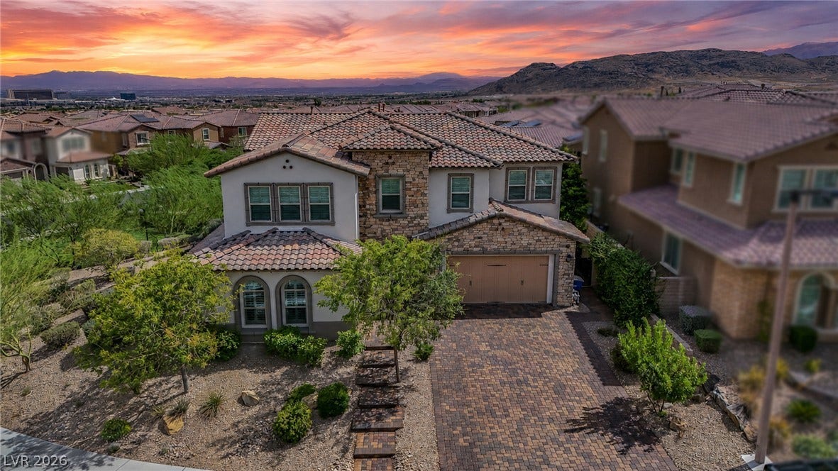 12013 Tramonto Avenue, Las Vegas, NV 89138 A paved driveway leads to this stone-accented exterior set against a mountain backdrop.