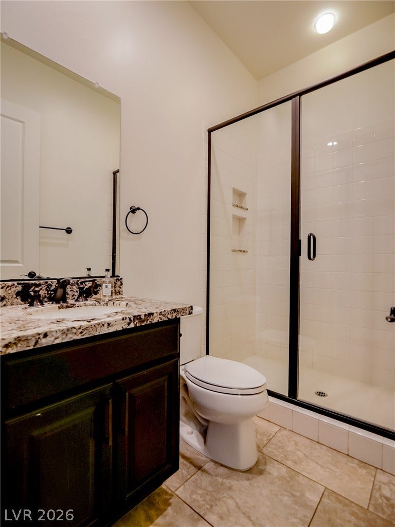 12013 Tramonto Avenue, Las Vegas, NV 89138 Tiled flooring and a glass-enclosed shower stall define this modern bathroom space.