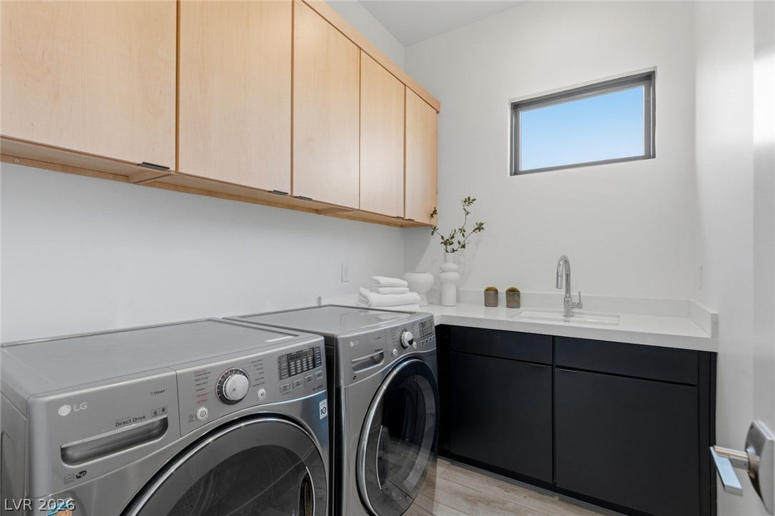 2208 Overlook Canyon Lane, Henderson, NV 89052 Functional laundry space featuring light wood cabinetry, a utility sink, and contemporary front-load appliances.