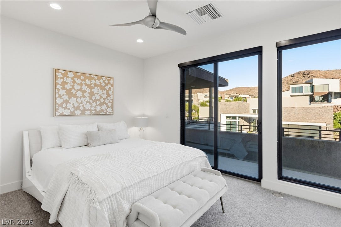 2208 Overlook Canyon Lane, Henderson, NV 89052 A tranquil bedroom with soft carpet flooring and a ceiling fan, offering direct access to an outdoor balcony.