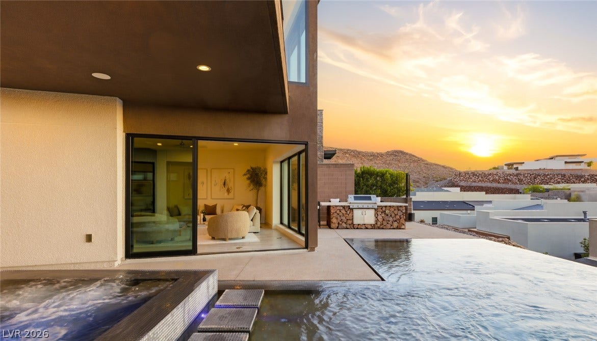 2208 Overlook Canyon Lane, Henderson, NV 89052 An inviting infinity pool and spa overlook a scenic mountain sunset.