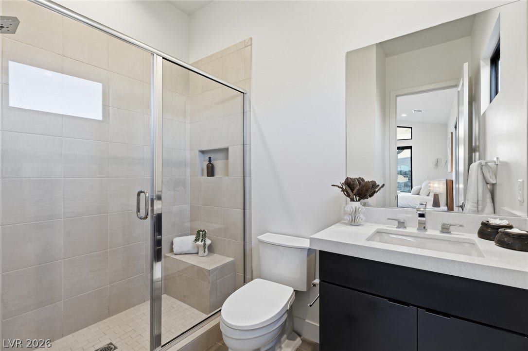 2208 Overlook Canyon Lane, Henderson, NV 89052 A well-appointed bathroom features a glass-enclosed shower, a sleek vanity, and a large wall mirror.