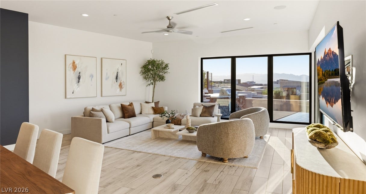 2208 Overlook Canyon Lane, Henderson, NV 89052 Natural light floods this living area through vast windows, showcasing beautiful wood flooring and high ceilings.