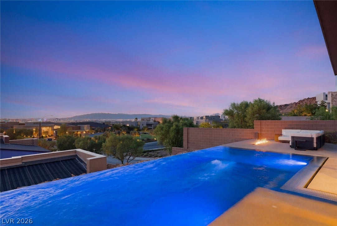 2208 Overlook Canyon Lane, Henderson, NV 89052 An inviting infinity pool offers a mesmerizing view of the distant cityscape and mountains under a twilight sky.