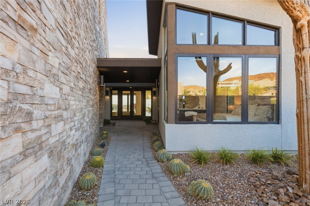 2208 Overlook Canyon Lane, Henderson, NV 89052 A striking modern entryway combines stone veneer, expansive windows, and desert landscaping.