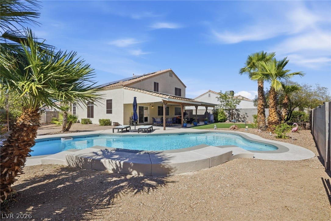 206 Oleander Place, Henderson, NV 89015 An inviting backyard oasis offers a sparkling in-ground pool, covered patio, and lush palm trees.