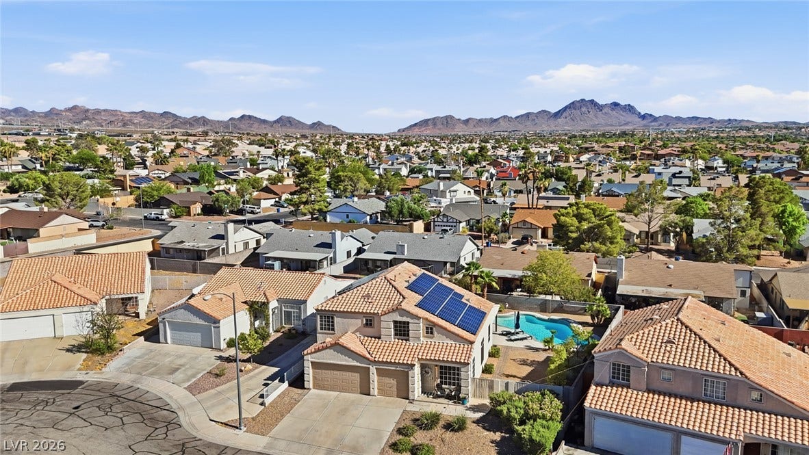 206 Oleander Place, Henderson, NV 89015 Aerial view of a community with a private pool and solar panels, nestled against a scenic mountain backdrop.