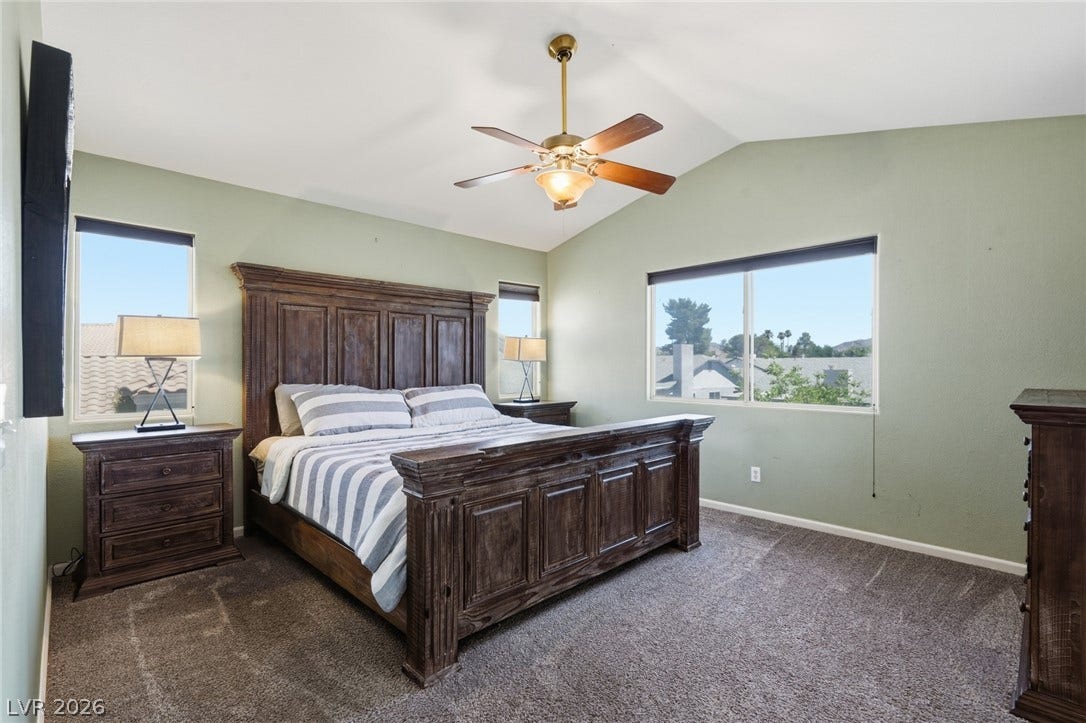 206 Oleander Place, Henderson, NV 89015 A comfortable bedroom with vaulted ceilings, featuring a large bed and ample natural light from multiple windows.