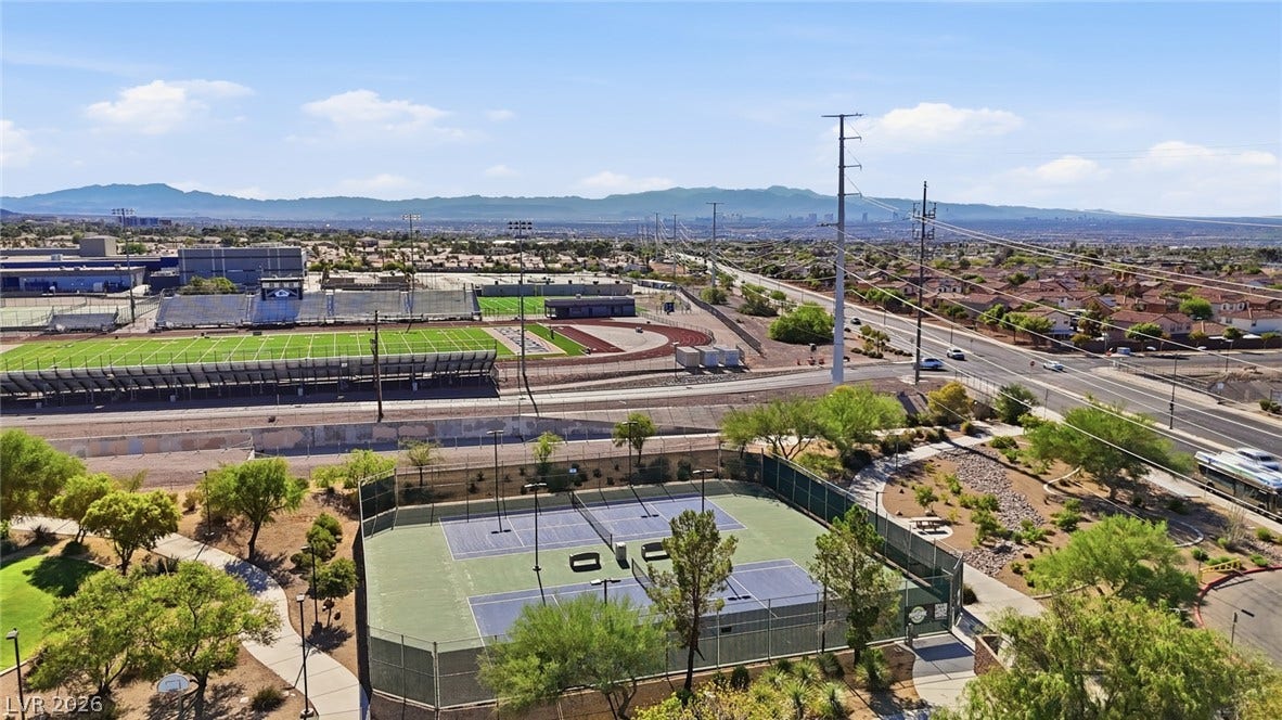 206 Oleander Place, Henderson, NV 89015 An aerial perspective reveals a vibrant tennis court, a scenic path, and distant residential areas.