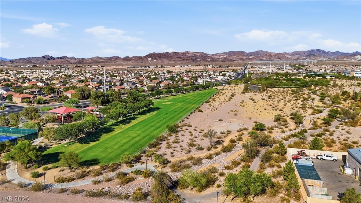206 Oleander Place, Henderson, NV 89015 An aerial perspective reveals a vibrant community nestled against distant mountains, featuring a verdant golf course and residential rooftops.