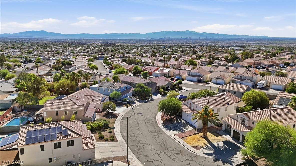 206 Oleander Place, Henderson, NV 89015 An aerial perspective reveals a vibrant neighborhood with residential homes set against a distant mountain and city skyline.