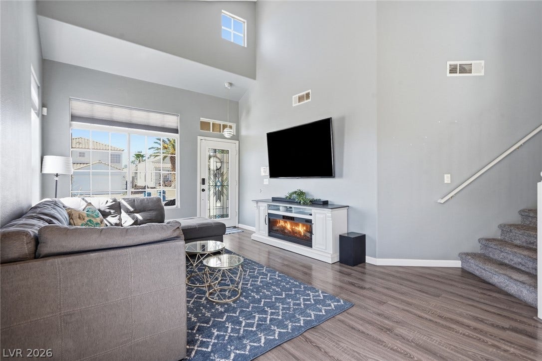 206 Oleander Place, Henderson, NV 89015 Natural light floods this inviting living area, featuring an electric fireplace and stylish wood-look flooring.