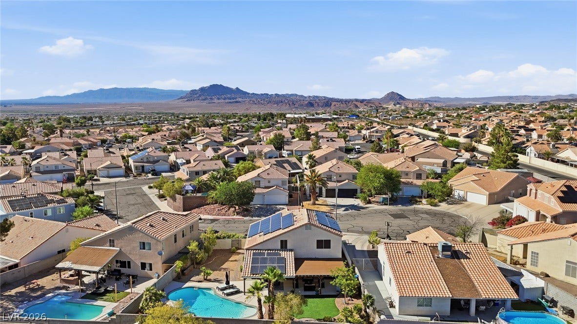 206 Oleander Place, Henderson, NV 89015 An aerial perspective reveals a vibrant neighborhood with mountain views and several homes featuring solar panels and backyard pools.